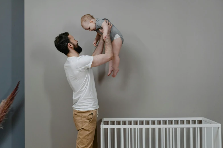 a man holding a baby up in the air, pexels contest winner, figuration libre, decoration, panels, plain background, bearded and built
