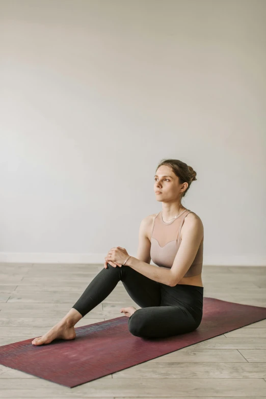 a woman sitting on a yoga mat in a room, unsplash, looking to the right, low quality photo, jodie bateman, half - length photo