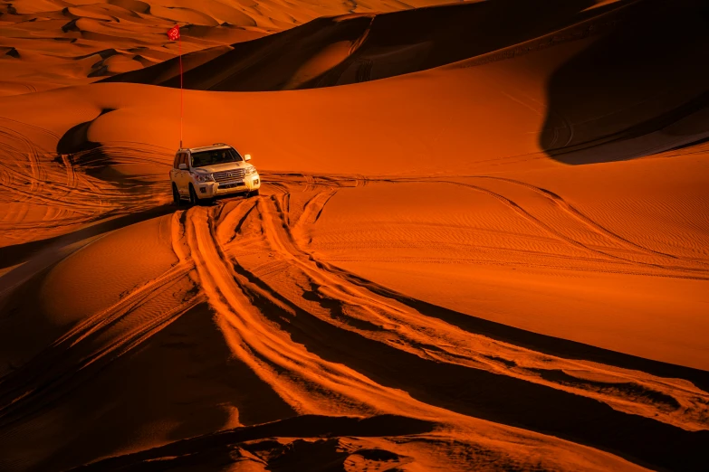 a vehicle that is driving in the sand, by Daniel Seghers, pexels contest winner, orange glow, sahara, light tan, thumbnail