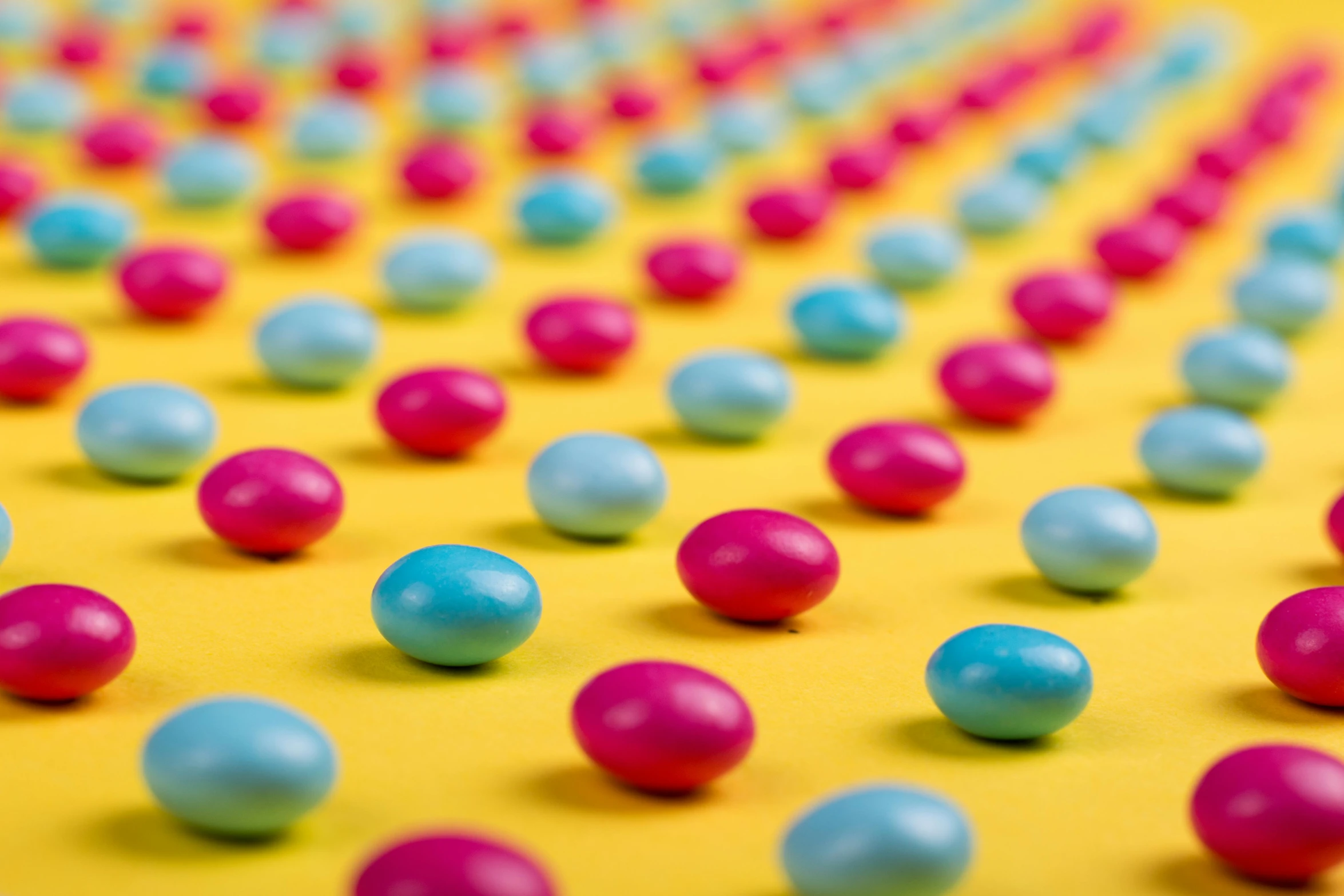 a bunch of candy balls sitting on top of a yellow surface, a picture, by Matt Cavotta, pexels, color field, cyan and magenta, studs, maths, beans