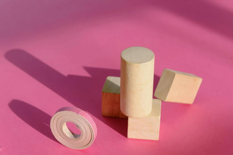 a couple of wooden blocks sitting on top of a pink surface, circular, 40mm tape, pink marble building, full product shot