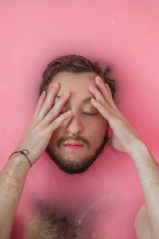 a man in a bathtub with his hands on his face, an album cover, trending on pexels, massurrealism, ((pink)), inflatable, unkempt beard, water eyes