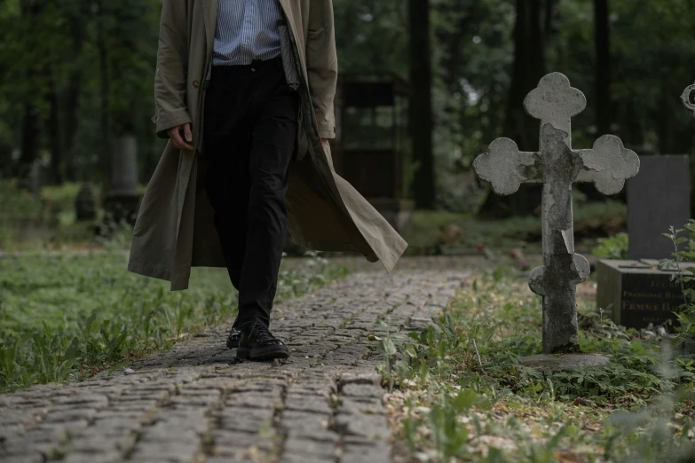 a man in a trench coat walking through a cemetery, pexels, realism, detective clothes, background image, stand on stone floor, [ theatrical ]