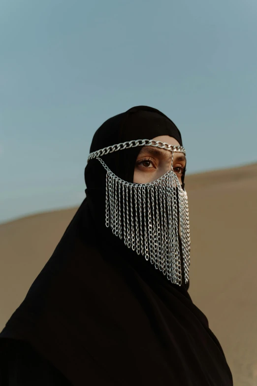 a woman wearing a black hijab in the desert, an album cover, inspired by Hedi Xandt, trending on pexels, chain mail, kris kuksi, balaclava, still from the film