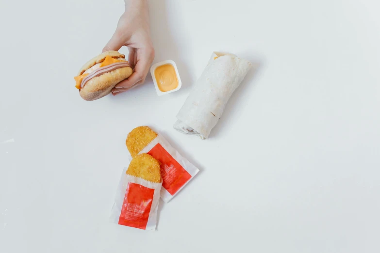 a person holding a hot dog and some condiments, a picture, unsplash, plasticien, white and orange, kfc, bao pnan, made of cheese