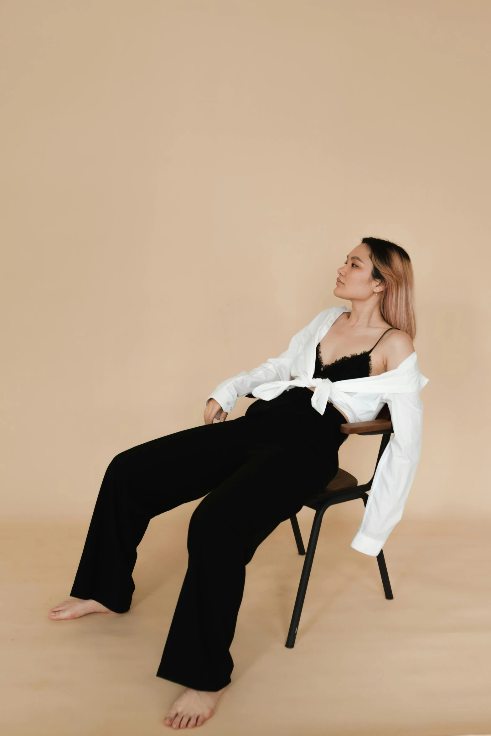 a woman sitting on a chair in a white shirt and black pants, inspired by Esaias Boursse, trending on pexels, jumpsuit, sleepy, uwu, sydney sweeney