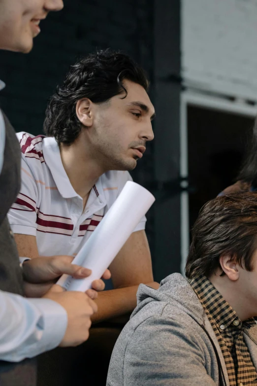 a group of people sitting around a laptop computer, trending on unsplash, academic art, young greek man, ( ( theatrical ) ), wide film still, islamic