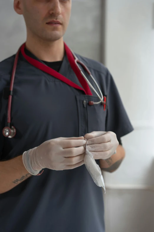 a man with a stethoscope in his hand, trending on reddit, wearing gloves, holds a small knife in hand, uniform, grey