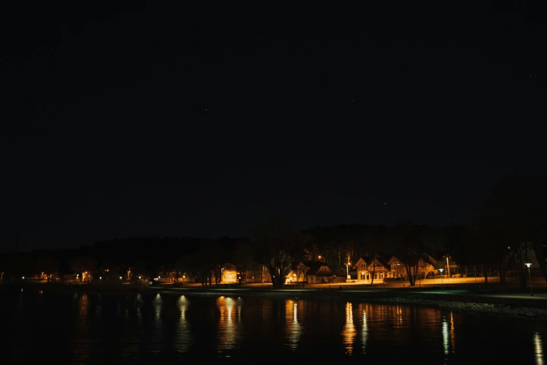 a view of a body of water at night, by Robert Storm Petersen, pexels contest winner, hurufiyya, midwest town, low quality photo, brown, alex kiesling