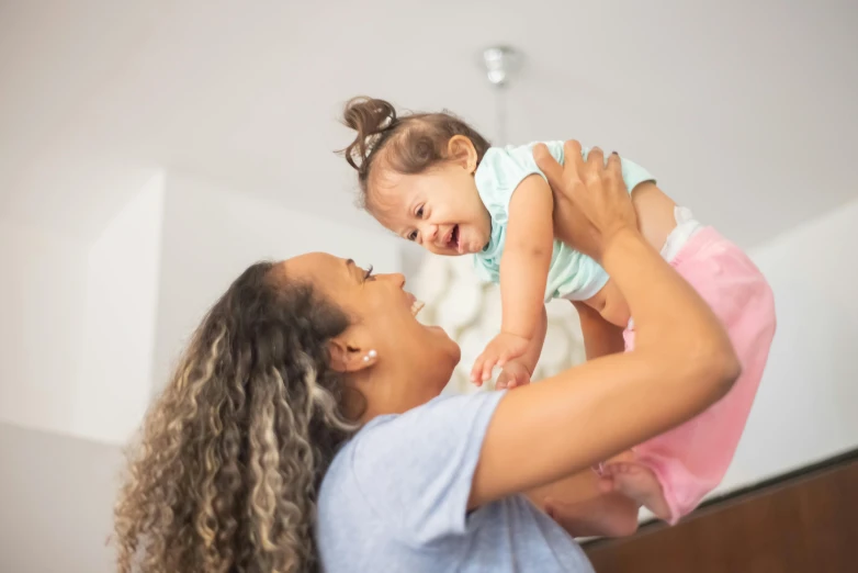 a woman holding a baby up in the air, manuka, avatar image, small, high quality image