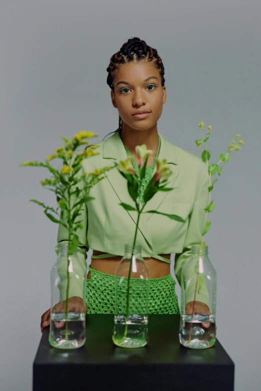 a woman holding three vases with plants in them, an album cover, willow smith young, photographed on ektachrome film, wearing green clothing, glass flowers