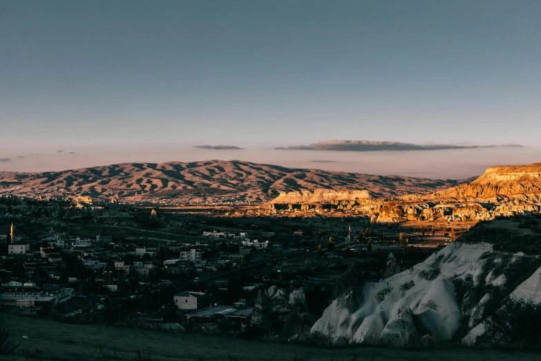 a view of a city with mountains in the background, unsplash contest winner, pamukkale, background image, low key light, paisley