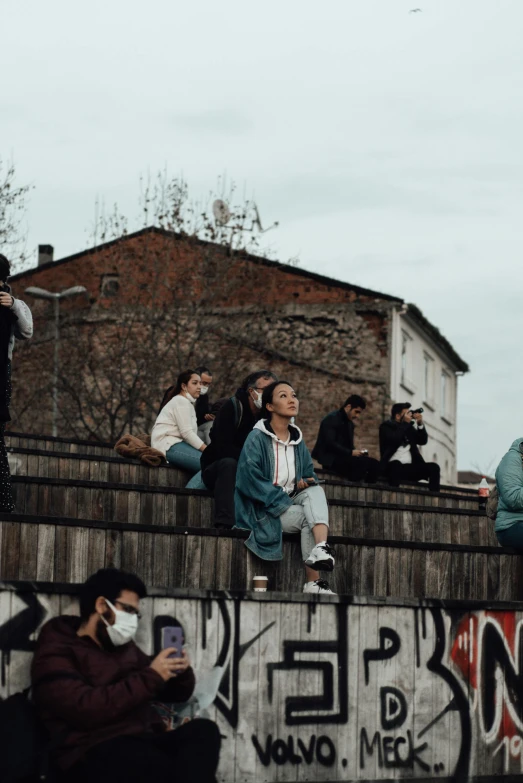 a group of people sitting on top of a wall, trending on pexels, graffiti, audience in the background, romanian, 😭 🤮 💕 🎀, human staring blankly ahead