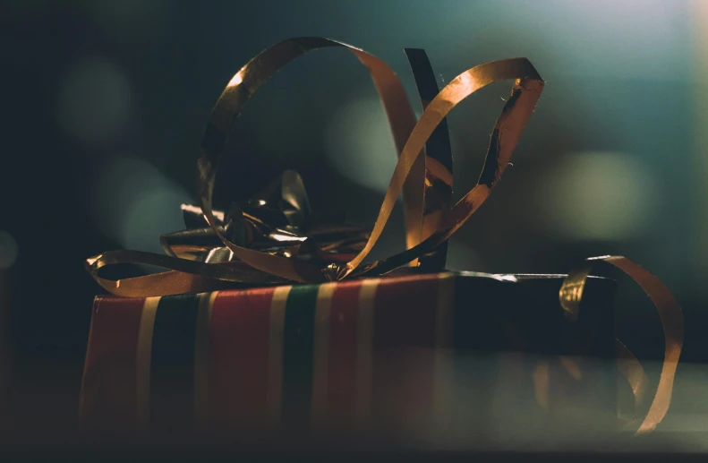 a wrapped gift sitting on top of a table, pexels contest winner, hurufiyya, golden ribbons, cinematic chiaroscuro, background bar, gold belt