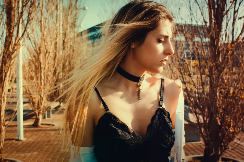 a beautiful young woman standing next to a tree, a photo, inspired by Elsa Bleda, trending on pexels, renaissance, black leather choker, wearing a camisole, brunette with dyed blonde hair, wearing black choker