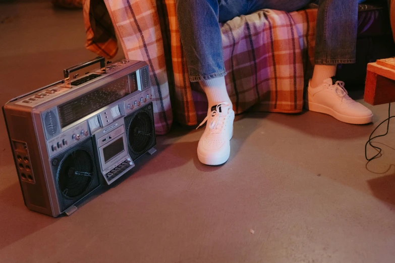 a person sitting on a couch next to a radio, inspired by Elsa Bleda, trending on pexels, graffiti, white shoes, cassette, on a checkered floor, chillin at the club together