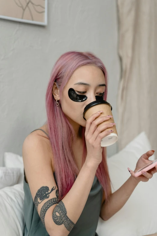 a woman sitting on a bed drinking a cup of coffee, a tattoo, inspired by Hedi Xandt, trending on pexels, wearing an eyepatch, ulzzang, skincare, snapchat photo