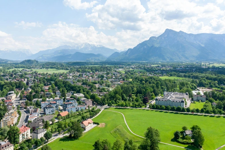 an aerial view of a town with mountains in the background, by Dietmar Damerau, pexels contest winner, visual art, green fields in the background, thumbnail, conde nast traveler photo, prussia