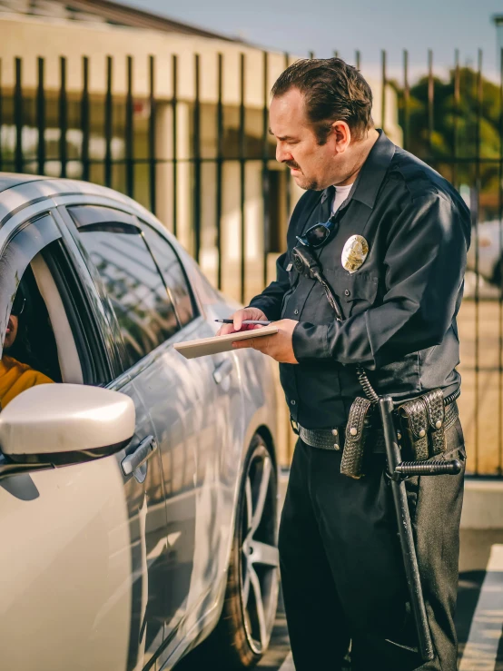 a man in a police uniform standing next to a car, by Dan Luvisi, unsplash, writing on a clipboard, 💣 💥💣 💥, california, high quality photo