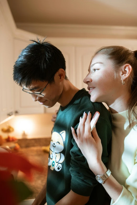 a woman standing next to a man in a kitchen, a picture, trending on pexels, half asian, holiday season, holding each other, gif