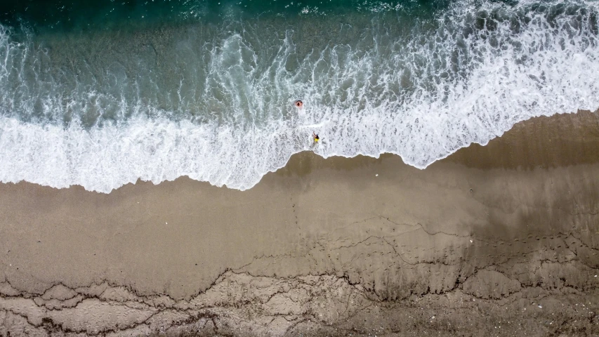 a man standing on top of a sandy beach next to the ocean, unsplash contest winner, minimalism, birds eye view, surfing, hollister ranch, currents