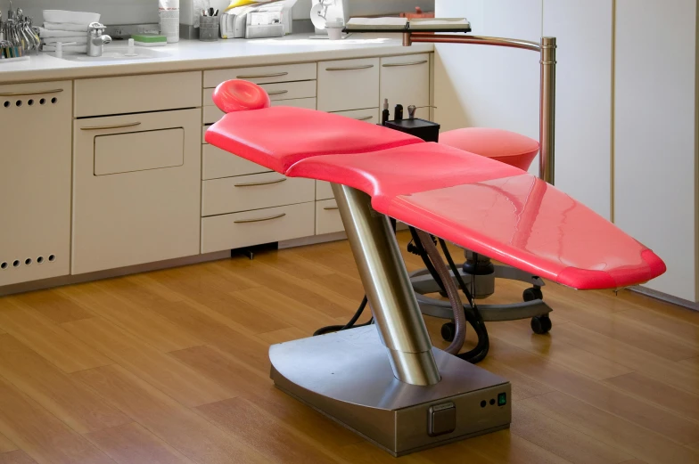 a red ironing board sitting on top of a wooden floor, by Évariste Vital Luminais, hurufiyya, surgery theatre, pink scheme, dentist, gray