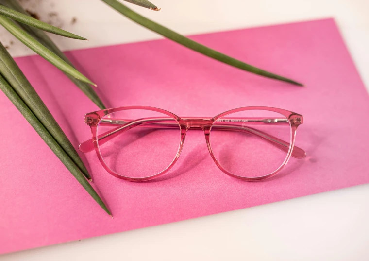 a pair of glasses sitting on top of a pink piece of paper