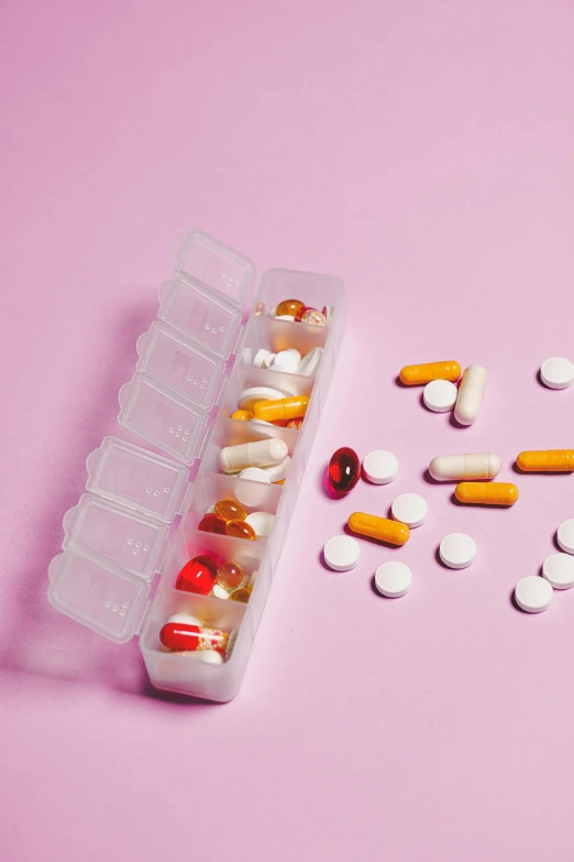 a container filled with lots of pills on top of a pink surface, a picture, by Julia Pishtar, pexels, multiple stories, orelsan, detailed product image, full-body
