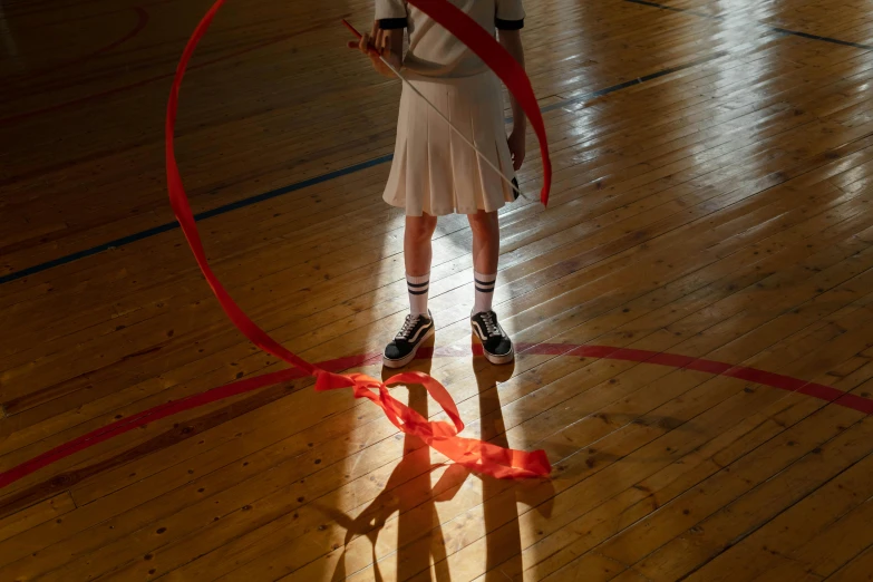 a girl standing in a gym holding a red ribbon, by Nathalie Rattner, pexels contest winner, casting long shadows, lighting her with a rim light, schools, spiraling