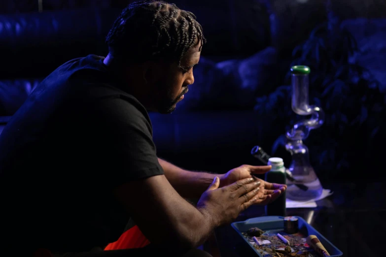 a man sitting at a table with a tray of food, pounds of weed, lowkey lighting, purple drank, praying