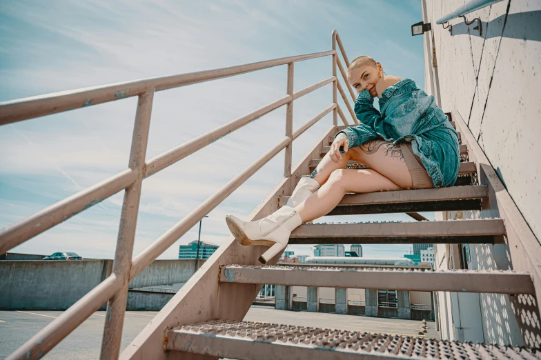 a woman sitting on top of a set of stairs, inspired by Elsa Bleda, pexels contest winner, lil peep, blue skies, she wears boots, photoshoot for skincare brand