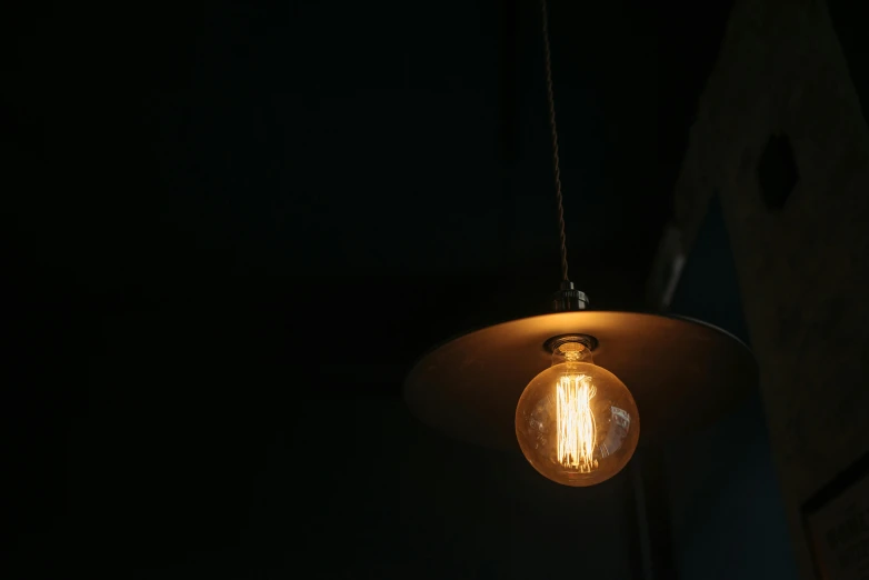 a light bulb hanging from a ceiling in a dark room, inspired by Elsa Bleda, unsplash, cafe lighting, a round minimalist behind, rembrandt lighting scheme, taken in the late 2010s