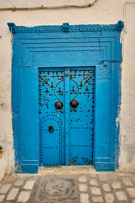 a blue door sitting on the side of a building, by Riad Beyrouti, les nabis, square, foil, rustic, tall