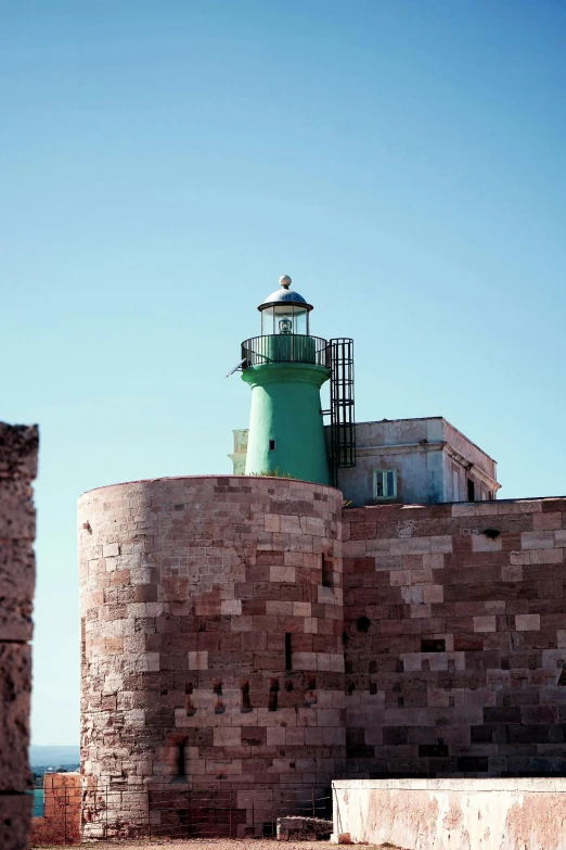 a green light house sitting on top of a brick wall, inspired by Wilhelm Marstrand, unsplash, romanesque, hydra, naples, silo, color”