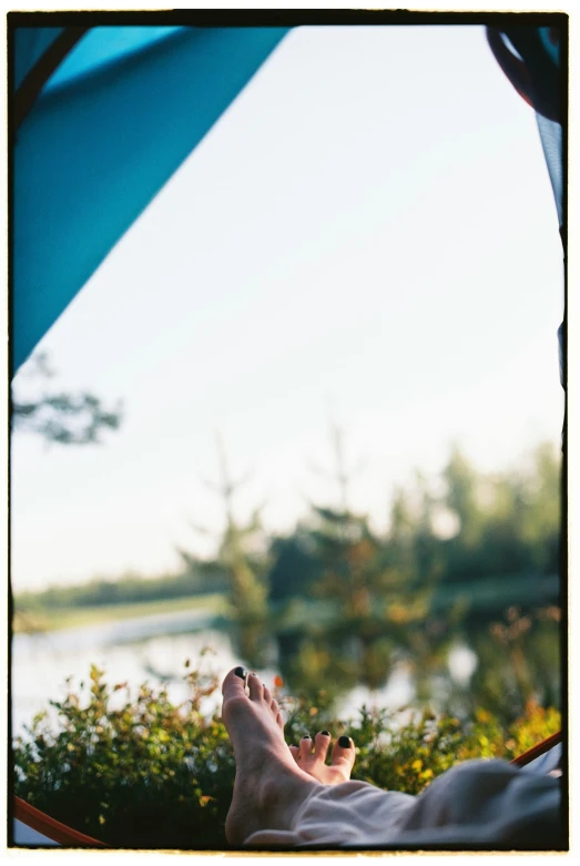 a person laying in a tent with their feet up, by Carey Morris, hasselblad film bokeh, summer lake setting, instagram story, minn