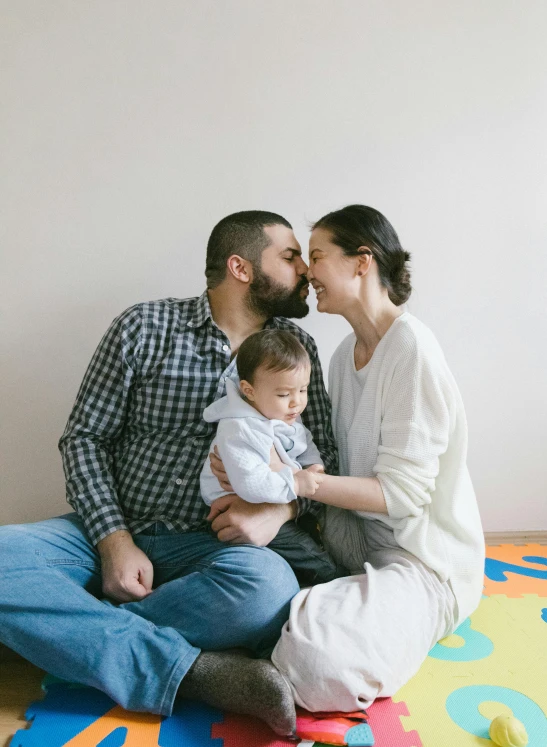 a man and woman sitting on the floor with a baby, profile image, square, bearded, hispanic