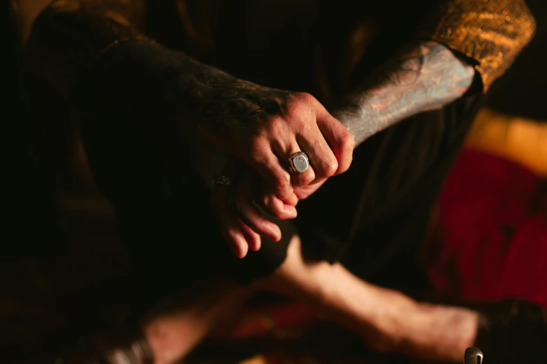 a close up of a person holding a person's hand, a tattoo, inspired by Elsa Bleda, trending on pexels, figure meditating close shot, sitting in a lounge, ring lit, tattooed man
