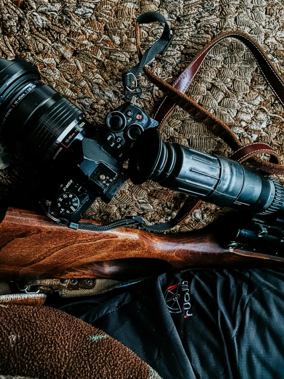 a camera and a rifle laying on the ground, by Adam Marczyński, leather hunting attire, full frame image, game ready, high angle close up shot