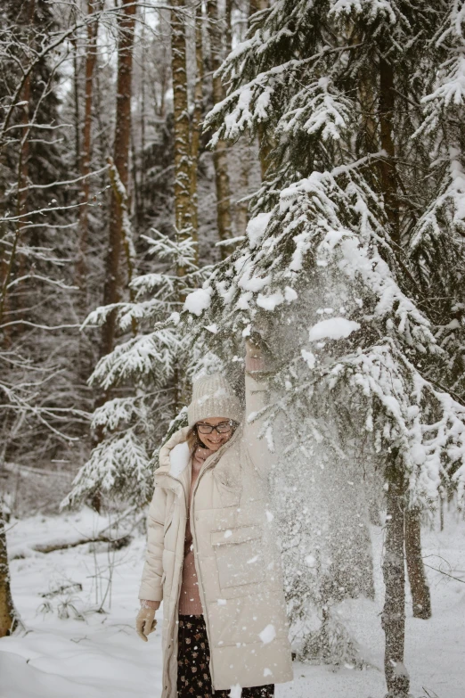 a woman standing in the snow next to a tree, cosy atmoshpere, burst of powders, swedish forest, russian style