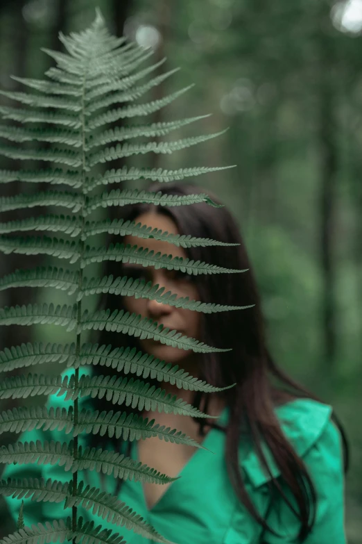 a woman holding a fern leaf in front of her face, inspired by Elsa Bleda, pexels contest winner, forest setting, avatar image, blurred photo, trending photo