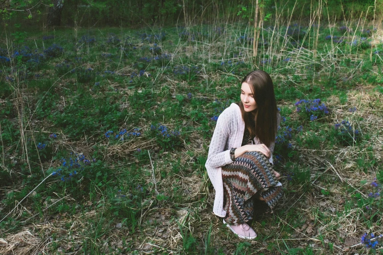 a woman sitting in the middle of a field, patterned clothing, in beautiful woods, hyacinth blooms surround her, instagram photo