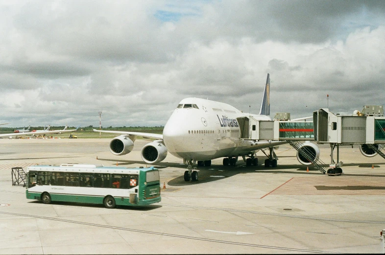 a large jetliner sitting on top of an airport tarmac, by Thomas Struth, hyperrealism, buses, 1999 photograph, multicoloured