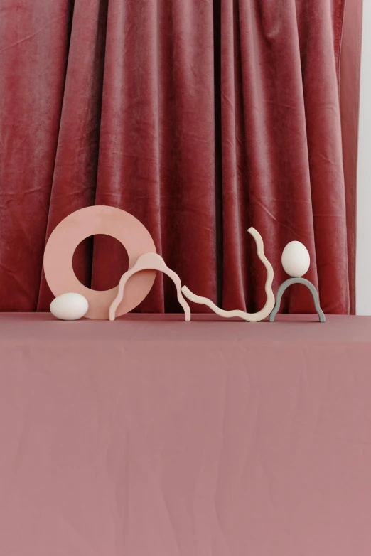 a pair of scissors sitting on top of a table, an abstract sculpture, inspired by Jean Arp, soft red tone colors, cups and balls, serpentine pose, victoria siemer
