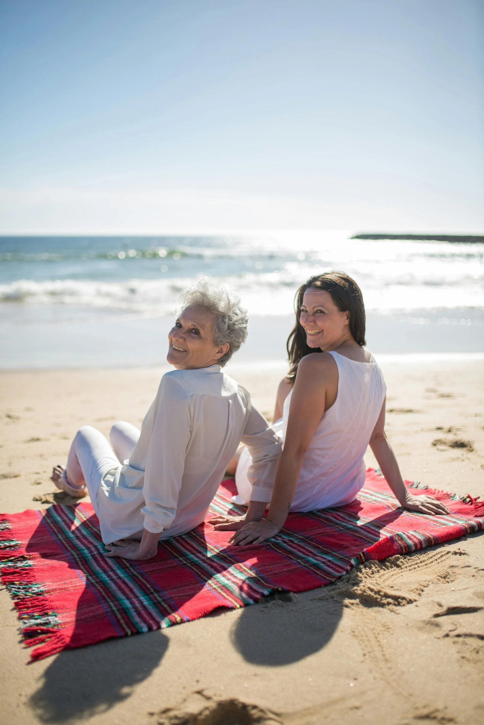 a man and a woman sitting on a blanket on the beach, manly, older woman, profile image