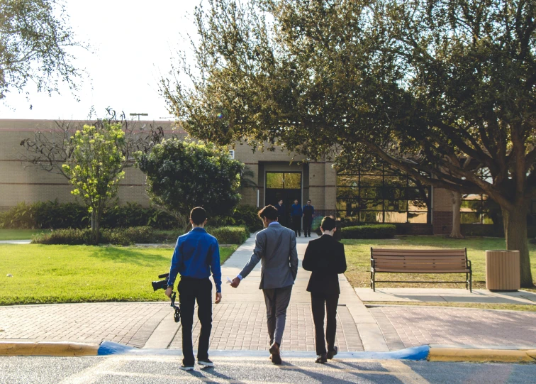 a group of people walking across a street, a photo, by Carey Morris, unsplash, academic art, cinematic blue and gold, research complex, tyler, three views