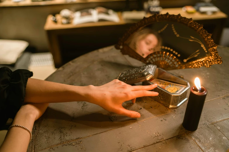 a person sitting at a table with a lit candle, by Emma Andijewska, pexels contest winner, hyperrealism, looking at the treasure box, inside mirror, an escape room in a small, holding a gold bag