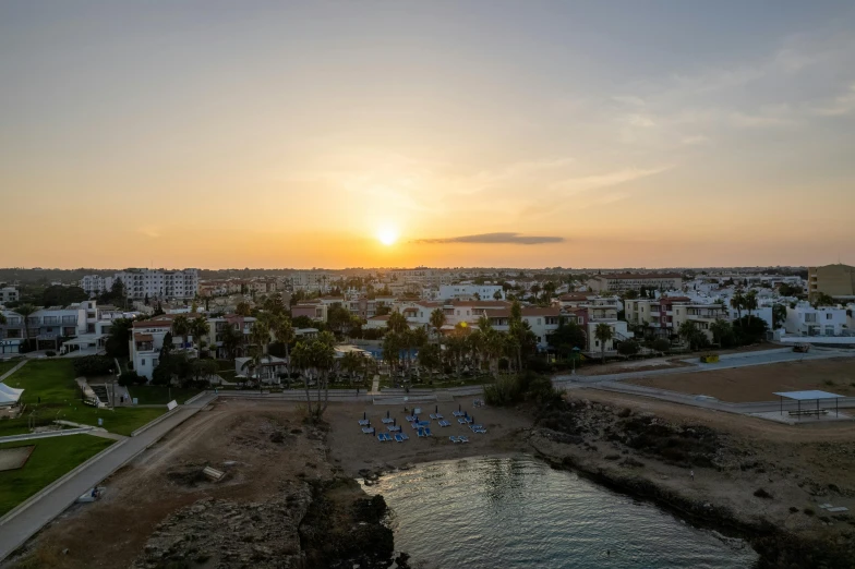 a large body of water next to a beach, by Daniel Lieske, pexels contest winner, cyprus, vista of a city at sunset, wide angle shot from above, high resolution photo