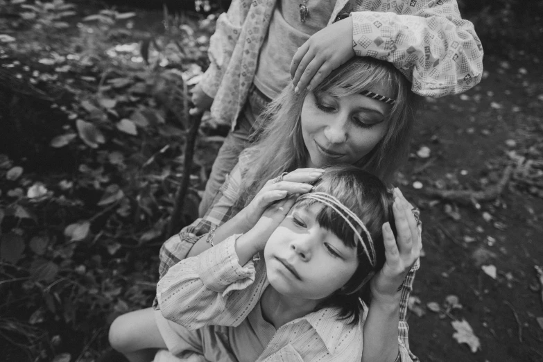 a black and white photo of a woman and a child, by Sergei Sviatchenko, pexels, renaissance, 1970s hippie cloth style, movie still of a tired, white witch, touching heads