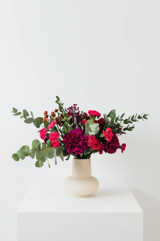 a white table topped with a vase filled with flowers, inspired by François Boquet, unsplash, red and magenta flowers, smooth matte, front facing shot, savanna