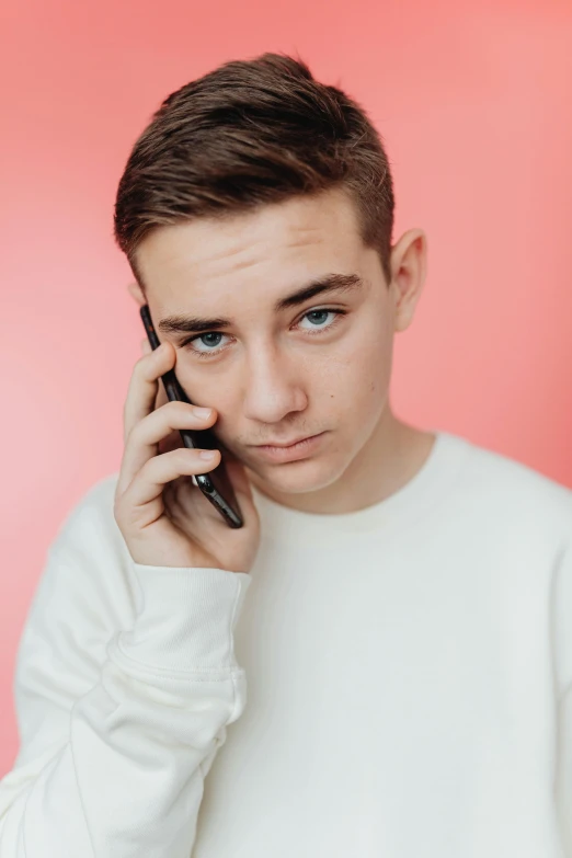 a young man holding a cell phone to his ear, by Cosmo Alexander, trending on pexels, realism, non binary model, aged 13, serious look, high collar